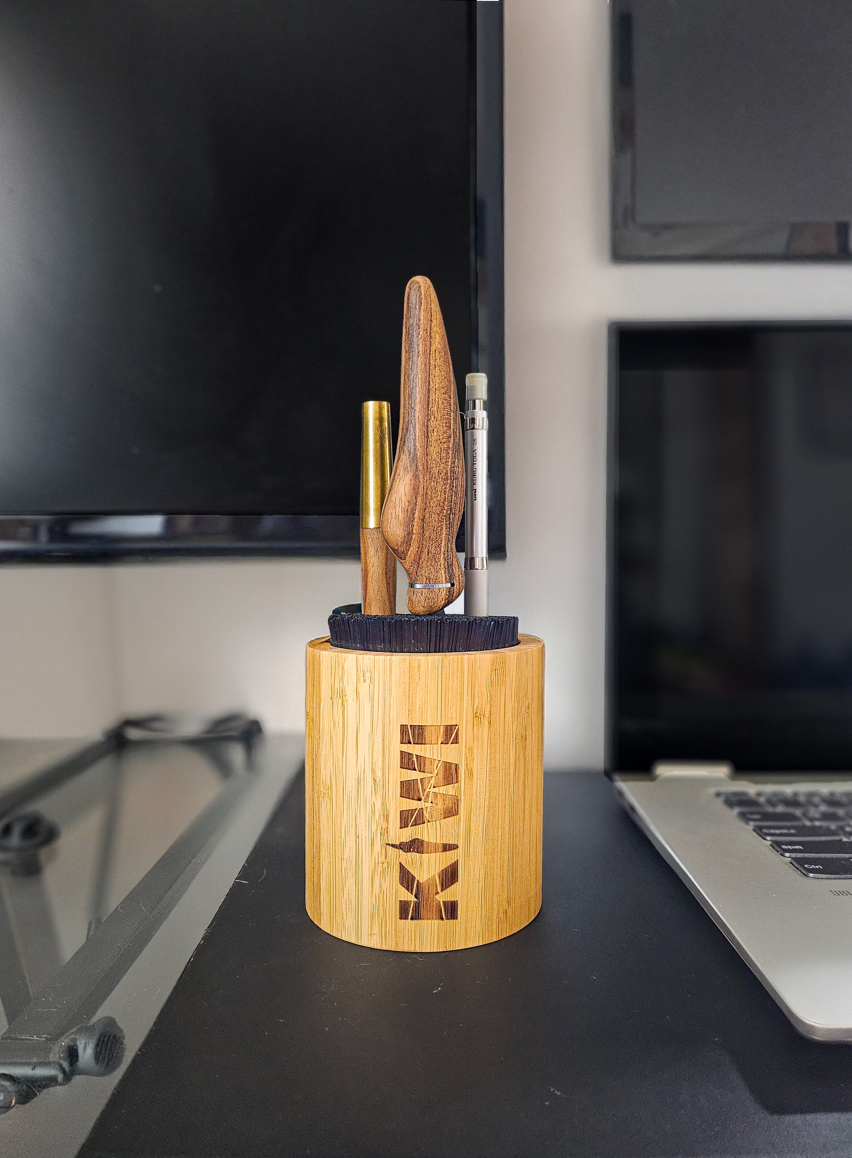 Kiwi Nest: On the desk — Kiwi Nest holding a wooden Kiwi knife and pencils, low evening light